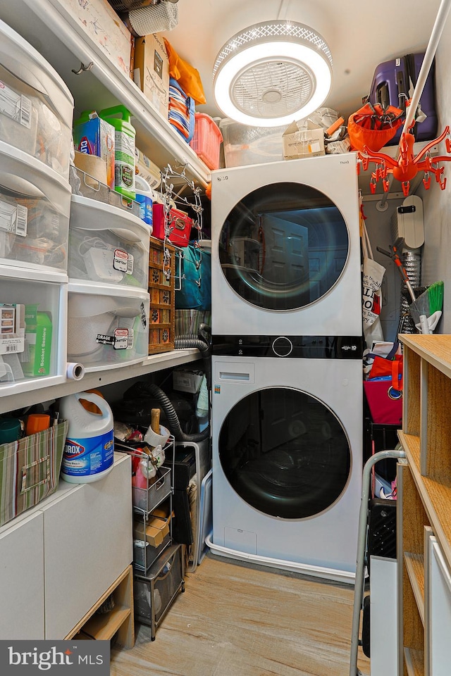 laundry room with light wood-type flooring and stacked washer and clothes dryer