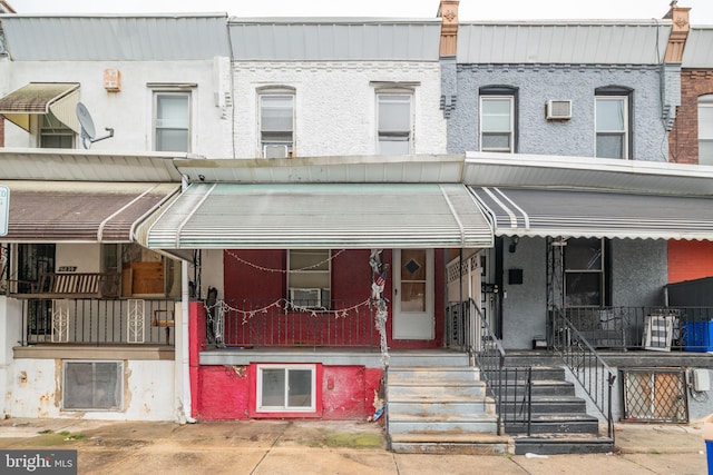 view of front of house with covered porch and a wall mounted air conditioner