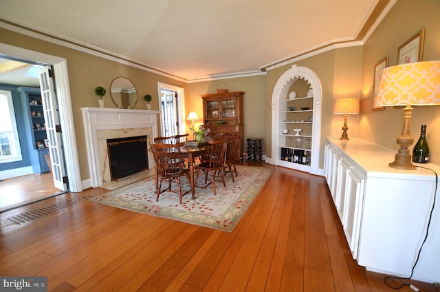 dining room featuring a fireplace, hardwood / wood-style flooring, and ornamental molding