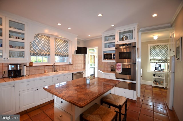 kitchen with dark tile patterned flooring, stainless steel appliances, backsplash, sink, and white cabinets