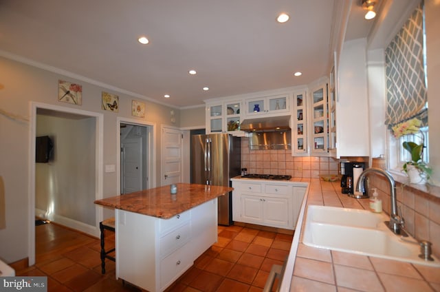 kitchen featuring white cabinetry, sink, a center island, stainless steel fridge, and decorative backsplash