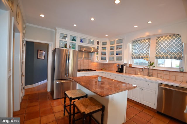 kitchen featuring decorative backsplash, appliances with stainless steel finishes, sink, white cabinetry, and a center island