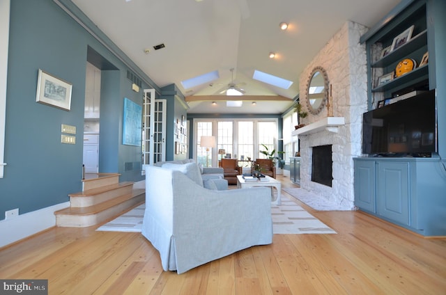 living room with ceiling fan, light hardwood / wood-style flooring, a fireplace, and high vaulted ceiling