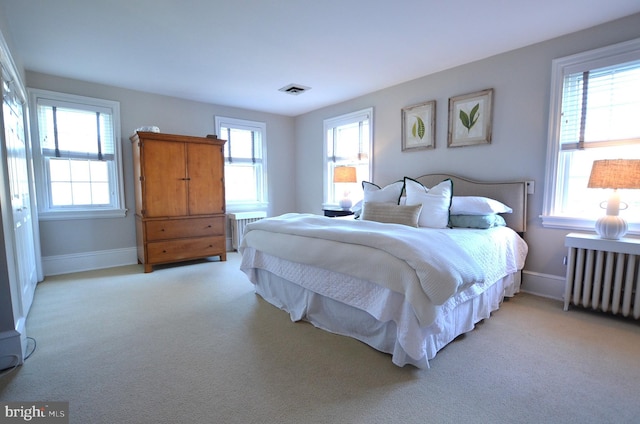 bedroom with radiator and light colored carpet