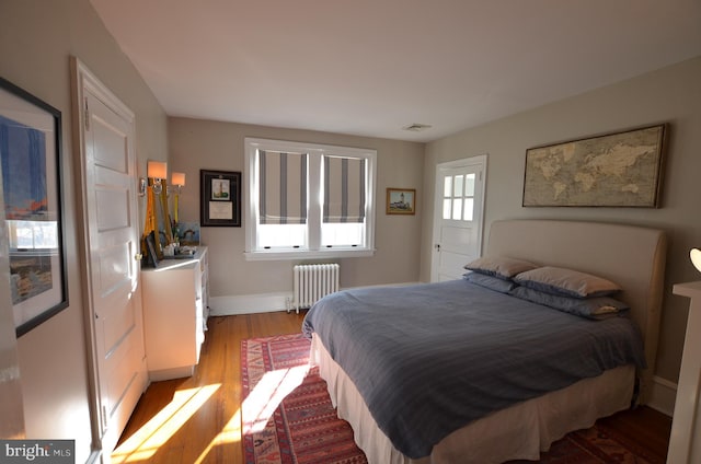 bedroom with radiator, multiple windows, and light hardwood / wood-style floors