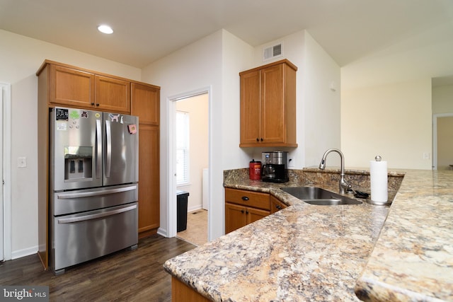 kitchen featuring light stone countertops, sink, dark hardwood / wood-style flooring, kitchen peninsula, and stainless steel fridge