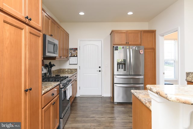 kitchen with light stone countertops, appliances with stainless steel finishes, and dark wood-type flooring