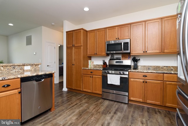 kitchen with dark hardwood / wood-style flooring, light stone counters, and appliances with stainless steel finishes