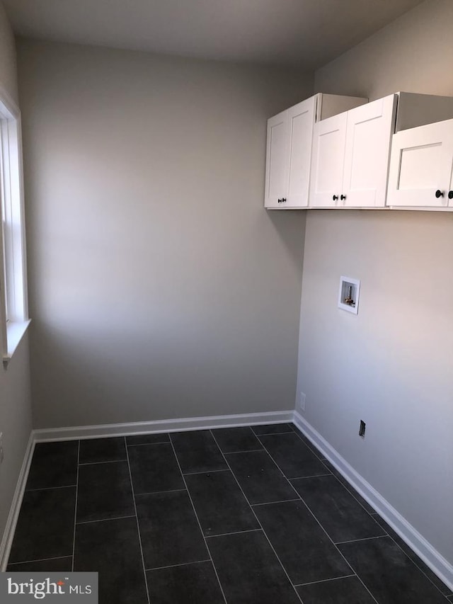 laundry room with hookup for a washing machine, dark tile patterned floors, and cabinets