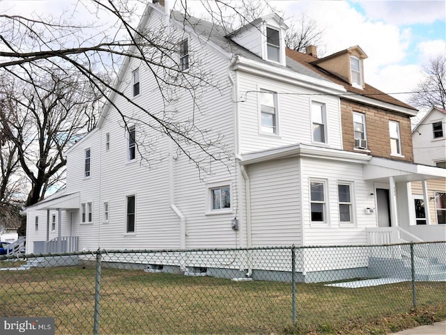 view of home's exterior with a fenced front yard, a chimney, and a lawn