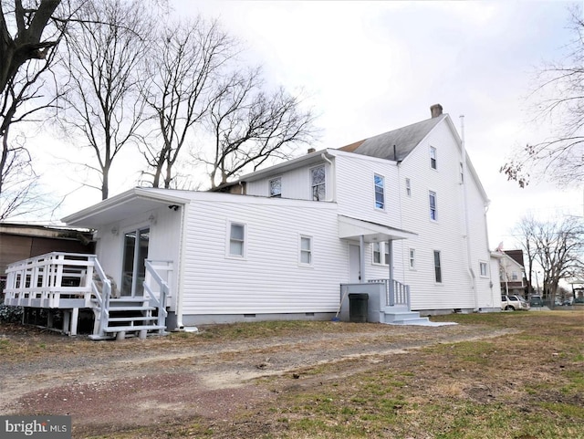 back of house with crawl space and a chimney