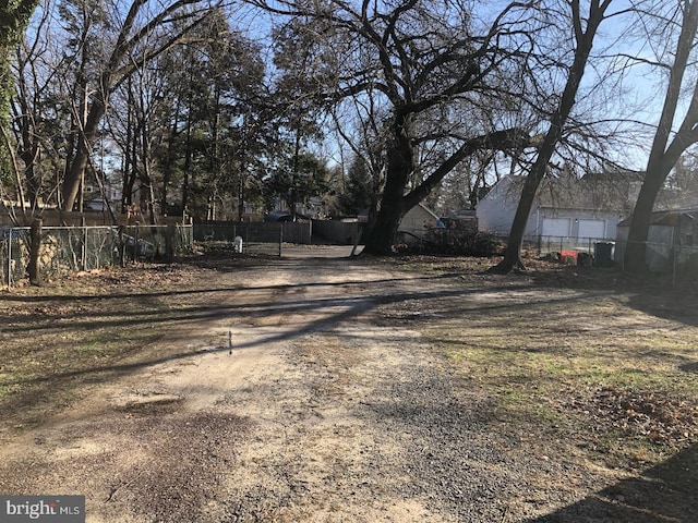 view of yard featuring dirt driveway and fence