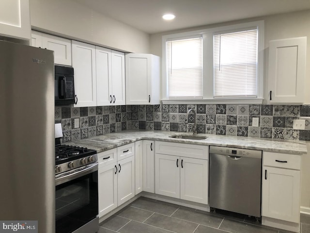 kitchen featuring stainless steel appliances, dark tile patterned flooring, a sink, and decorative backsplash