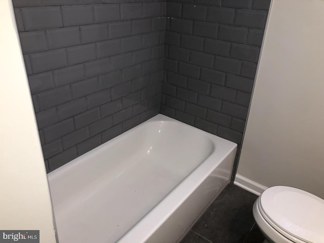 full bathroom with toilet, baseboards, and a bath