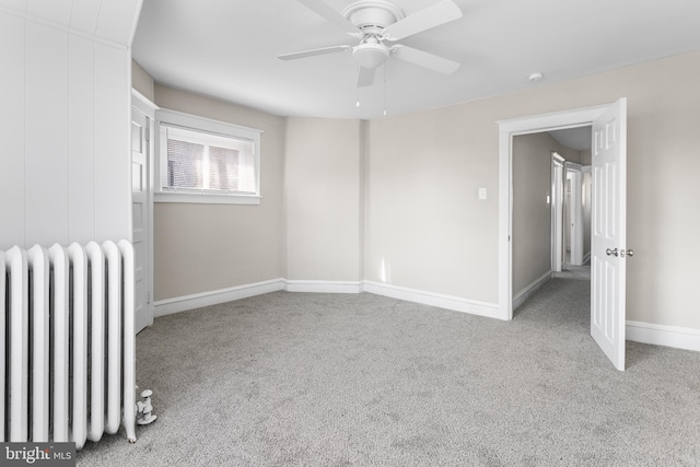 carpeted spare room with ceiling fan and radiator