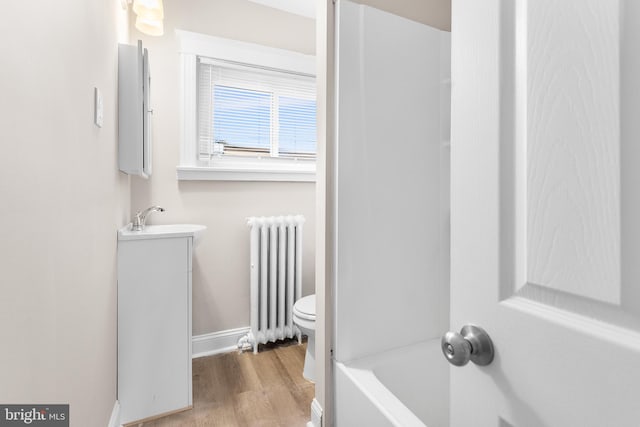 bathroom featuring hardwood / wood-style flooring, toilet, a washtub, radiator heating unit, and vanity