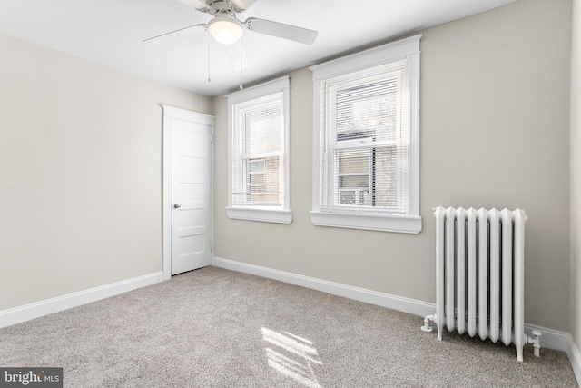 empty room with ceiling fan, radiator, and light carpet