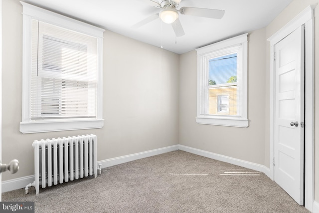 carpeted spare room featuring radiator and ceiling fan