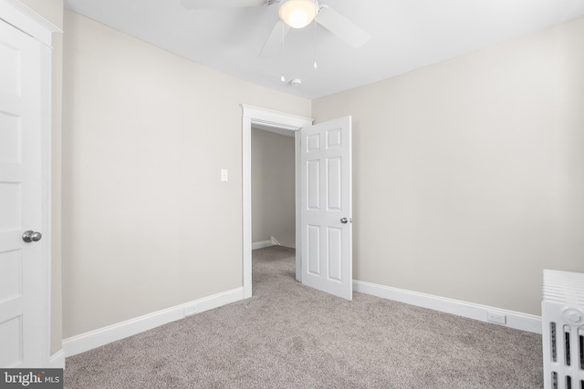 interior space featuring ceiling fan, radiator, and light carpet