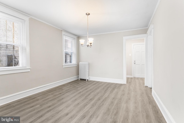 unfurnished dining area featuring ornamental molding, light hardwood / wood-style flooring, radiator, and a notable chandelier