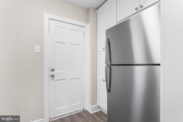 kitchen with dark wood-type flooring, stainless steel fridge, and white cabinetry