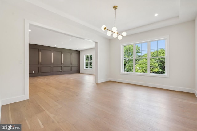 unfurnished living room with light hardwood / wood-style floors and a chandelier