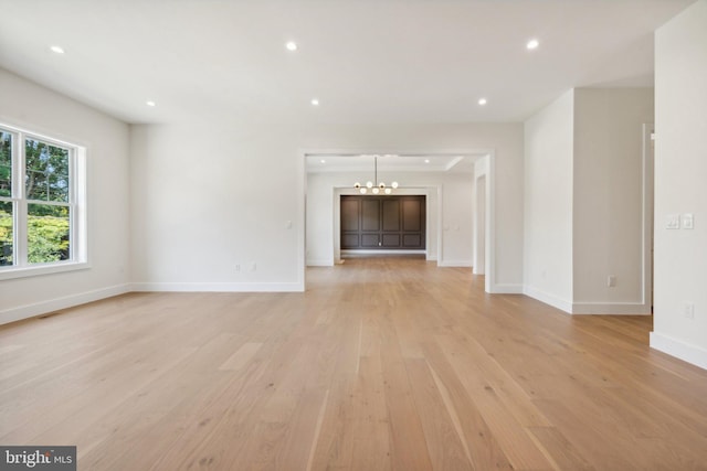 unfurnished living room featuring light hardwood / wood-style floors and a chandelier