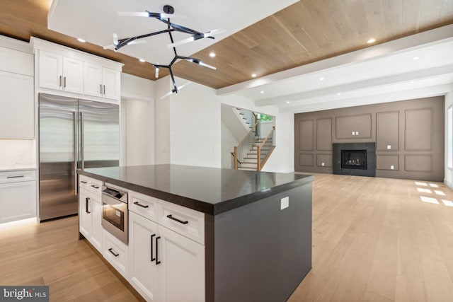 kitchen featuring white cabinetry, a spacious island, stainless steel built in fridge, and light wood-type flooring