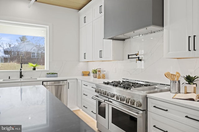 kitchen with appliances with stainless steel finishes, sink, white cabinets, and backsplash