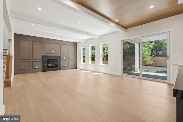 unfurnished living room featuring beam ceiling and light wood-type flooring