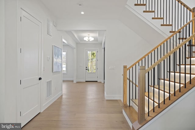 foyer entrance featuring light wood-type flooring and a chandelier