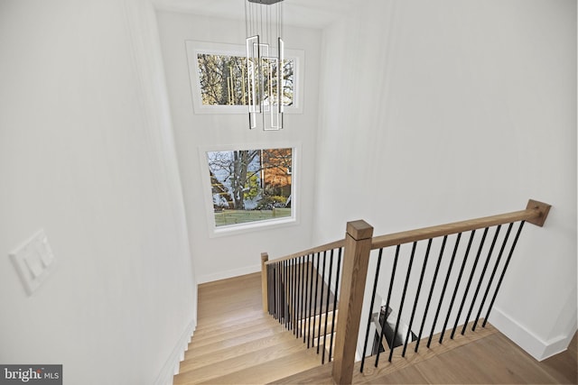 staircase with an inviting chandelier and hardwood / wood-style flooring