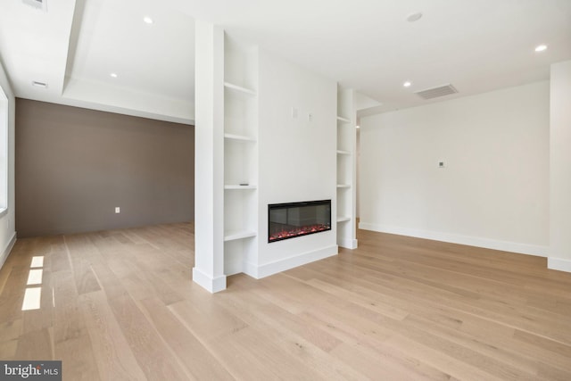 unfurnished living room with built in shelves and light hardwood / wood-style flooring