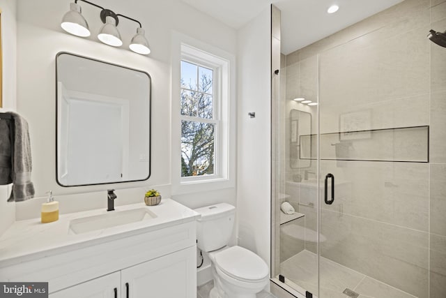 bathroom featuring vanity, toilet, and a shower with door