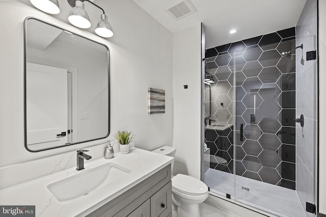 bathroom featuring vanity, a shower with door, and toilet