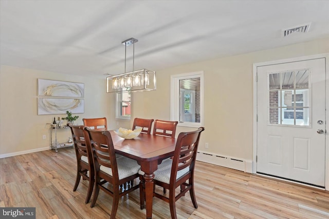 dining room featuring a notable chandelier, a baseboard heating unit, a healthy amount of sunlight, and light hardwood / wood-style floors