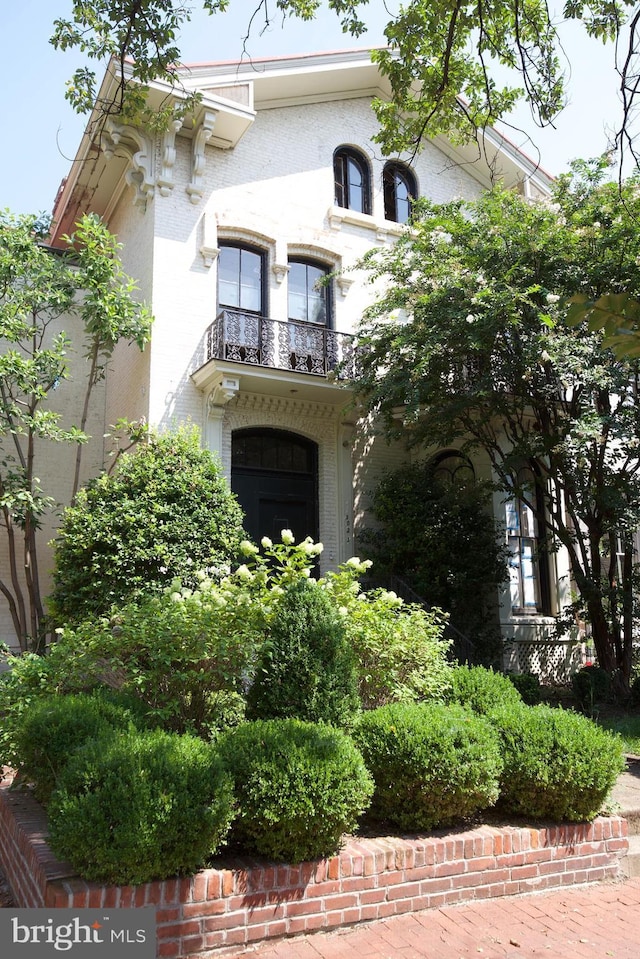 view of front facade featuring a balcony and brick siding