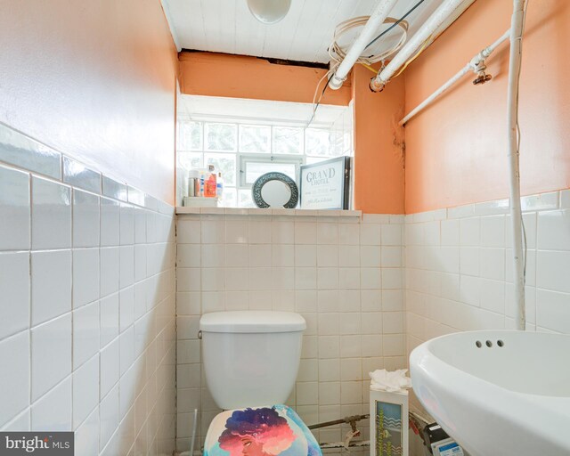 bathroom with sink, tile walls, and toilet