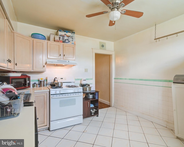 kitchen featuring ceiling fan, tile walls, light tile patterned flooring, light brown cabinetry, and white gas stove