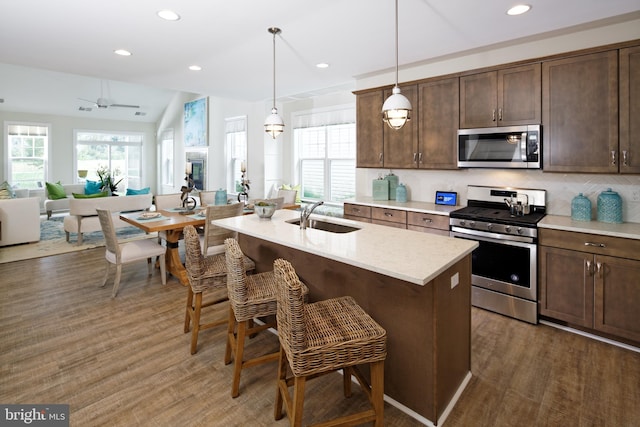 kitchen with sink, stainless steel appliances, dark wood-type flooring, and vaulted ceiling