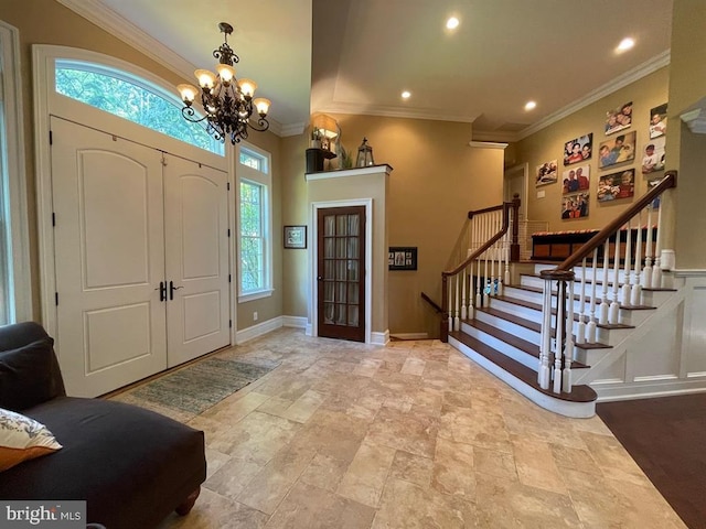 tiled entryway featuring ornamental molding, a chandelier, and plenty of natural light