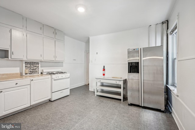 kitchen featuring stainless steel refrigerator with ice dispenser, white gas range, and white cabinets