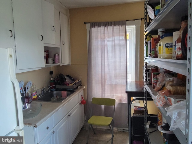 kitchen with white refrigerator, white cabinetry, sink, and a wealth of natural light