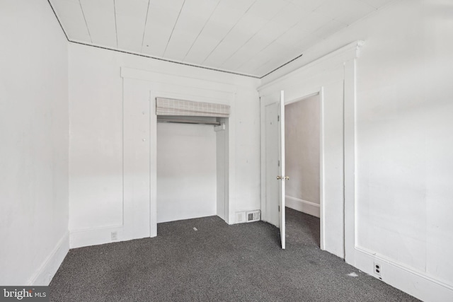 unfurnished bedroom featuring a closet and dark colored carpet