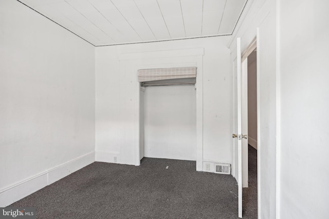 unfurnished bedroom featuring a closet and dark colored carpet