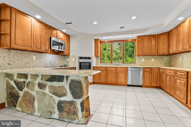 kitchen with light stone counters, kitchen peninsula, appliances with stainless steel finishes, and backsplash