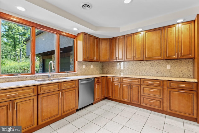 kitchen with light stone counters, backsplash, light tile patterned floors, stainless steel dishwasher, and sink