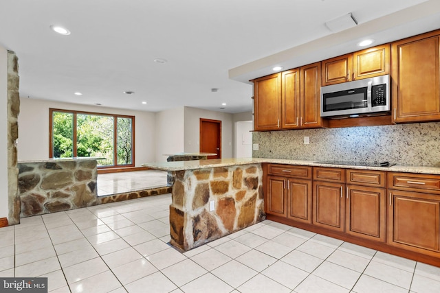 kitchen featuring light stone countertops, kitchen peninsula, light tile patterned floors, and black electric cooktop