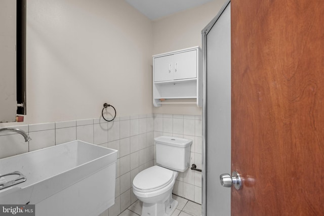 bathroom featuring tile walls, toilet, sink, and tile patterned floors