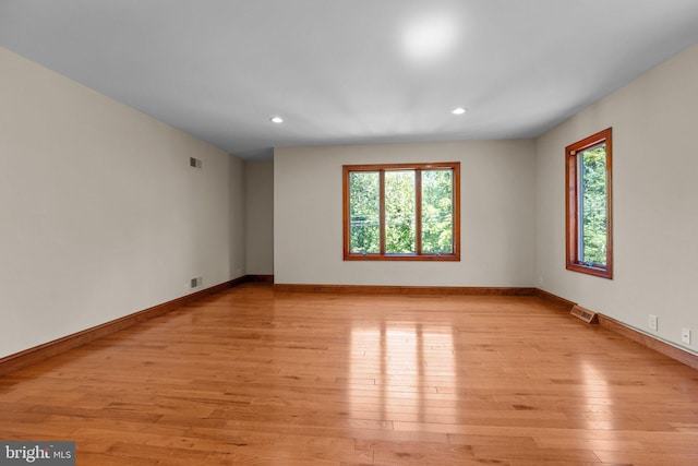 empty room with light hardwood / wood-style flooring and plenty of natural light